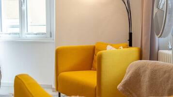 A room with a yellow sofa, a floor lamp, and a window with curtains.