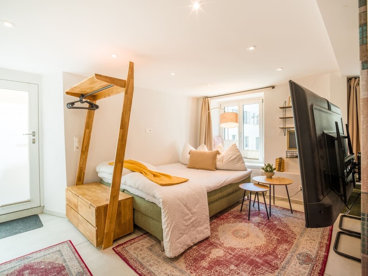 Un dormitorio con una cama litera, una mesita pequeña, un televisor y una ventana con cortinas.