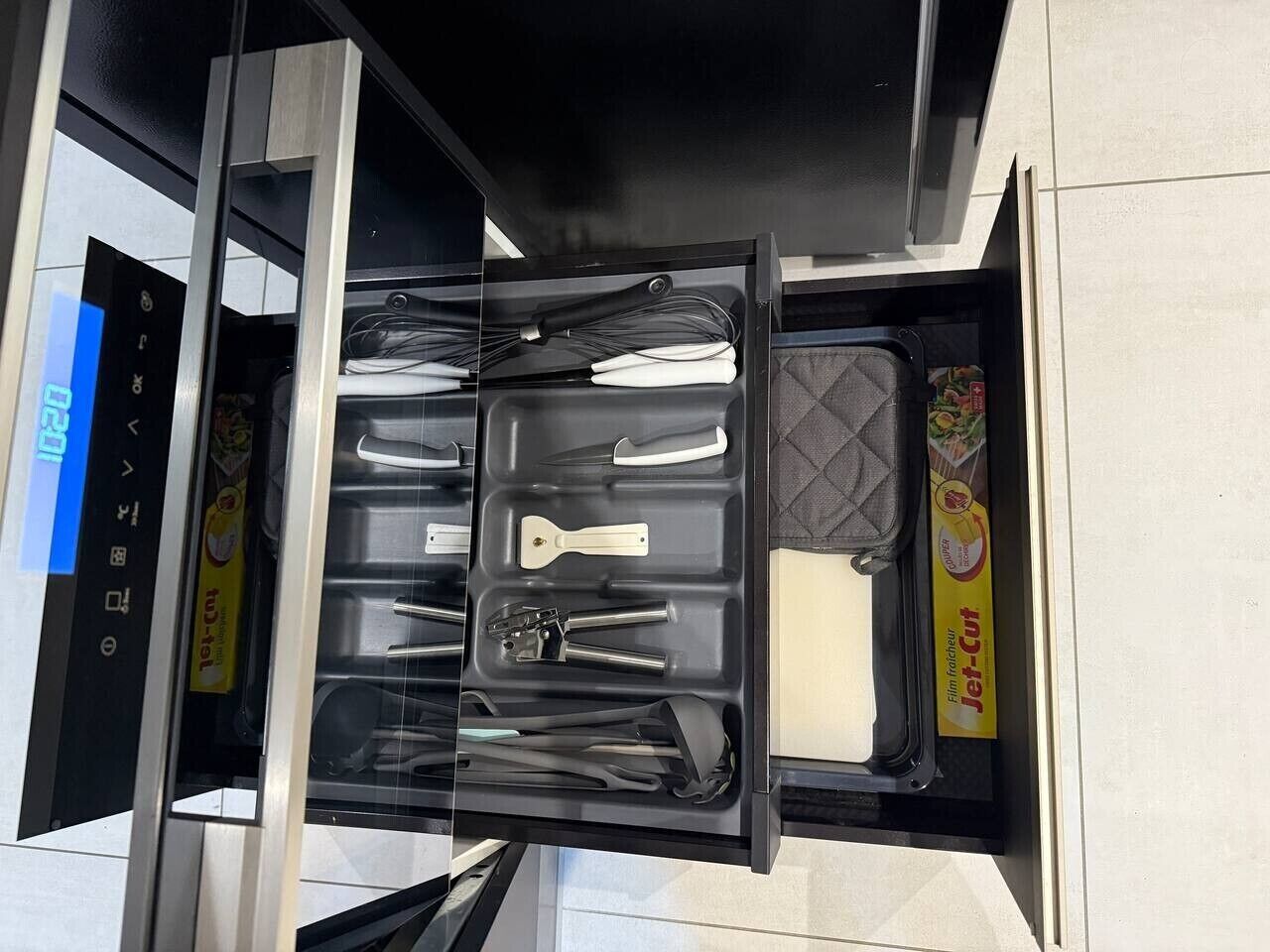 Un cajón de cocina con utensilios y envases de Jet-Cut congelados.