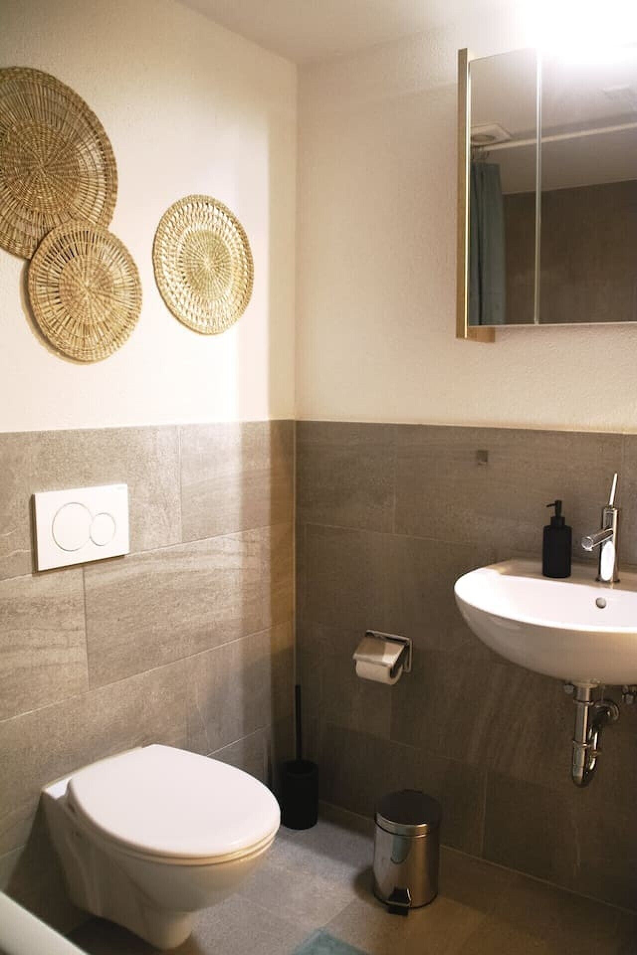 Een badkamer met toilet, wastafel en twee decoratieve items aan de muur.