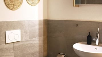 Een badkamer met toilet, wastafel en twee decoratieve items aan de muur.