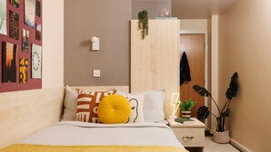 Ein ordentlich eingerichtetes Schlafzimmer mit Bett, Nachttisch und Wandregal.