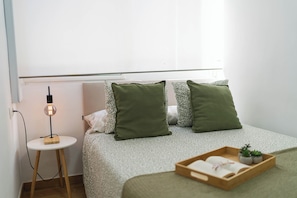 A neatly arranged bedroom with a bed, pillows, a bedside table, a lamp, and a tray with a book and plants. - CENTRAL APARTMENT, 12 MIN. AWAY FROM THE BEACH, (Almeria)