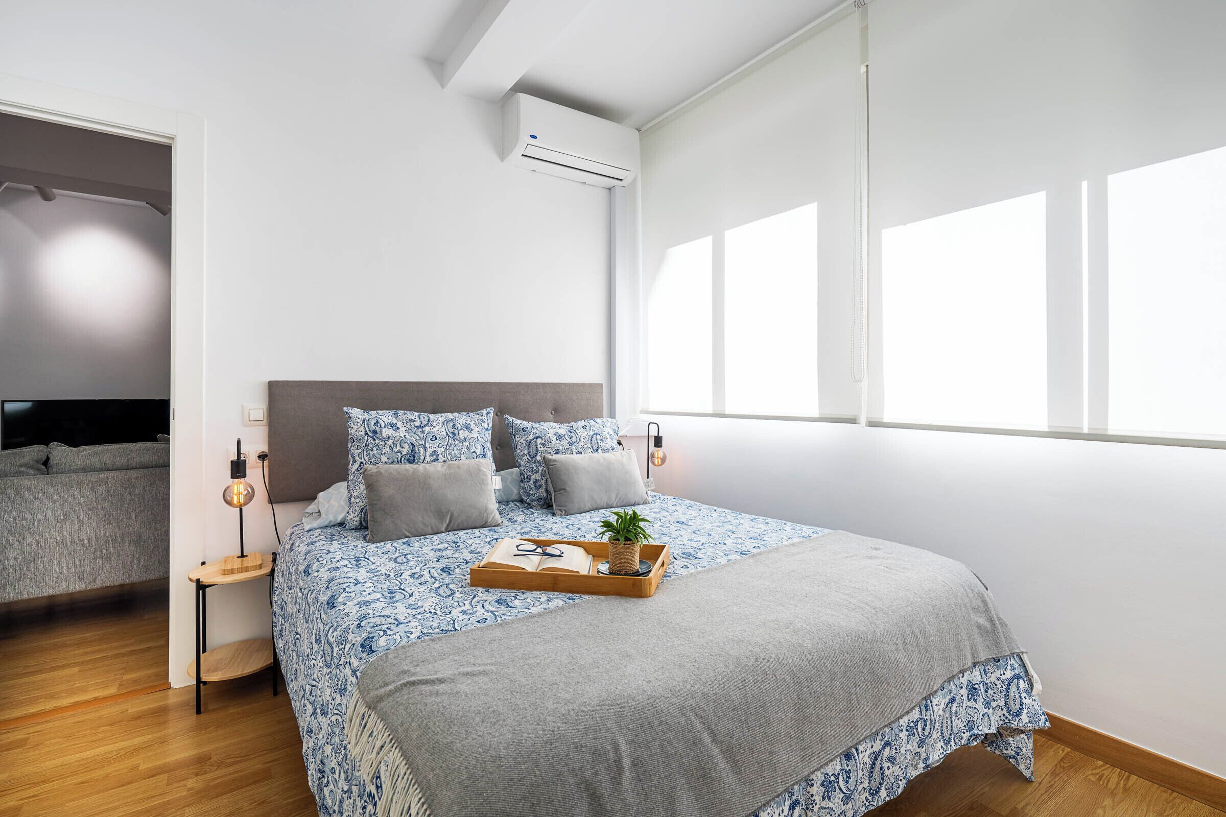Een slaapkamer met een bed, nachtkastjes, een raam en een airconditioning.
