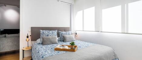 Een slaapkamer met een bed, nachtkastjes, een raam en een airconditioning.
