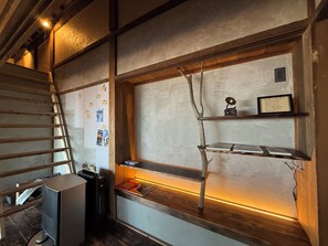 A room with a wooden ladder, a desk with a computer, and shelves with decorative items.