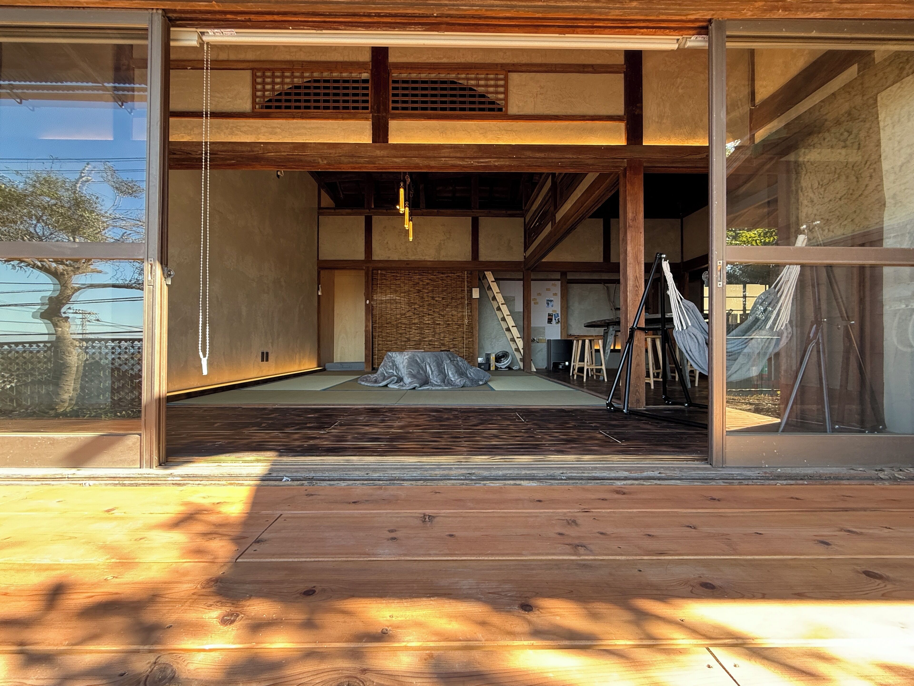 Ein traditionelles japanisches Interieur mit Tatami-Böden, einer niedrigen Holzbalkendecke und einer Schiebetür zu einem Balkon.
