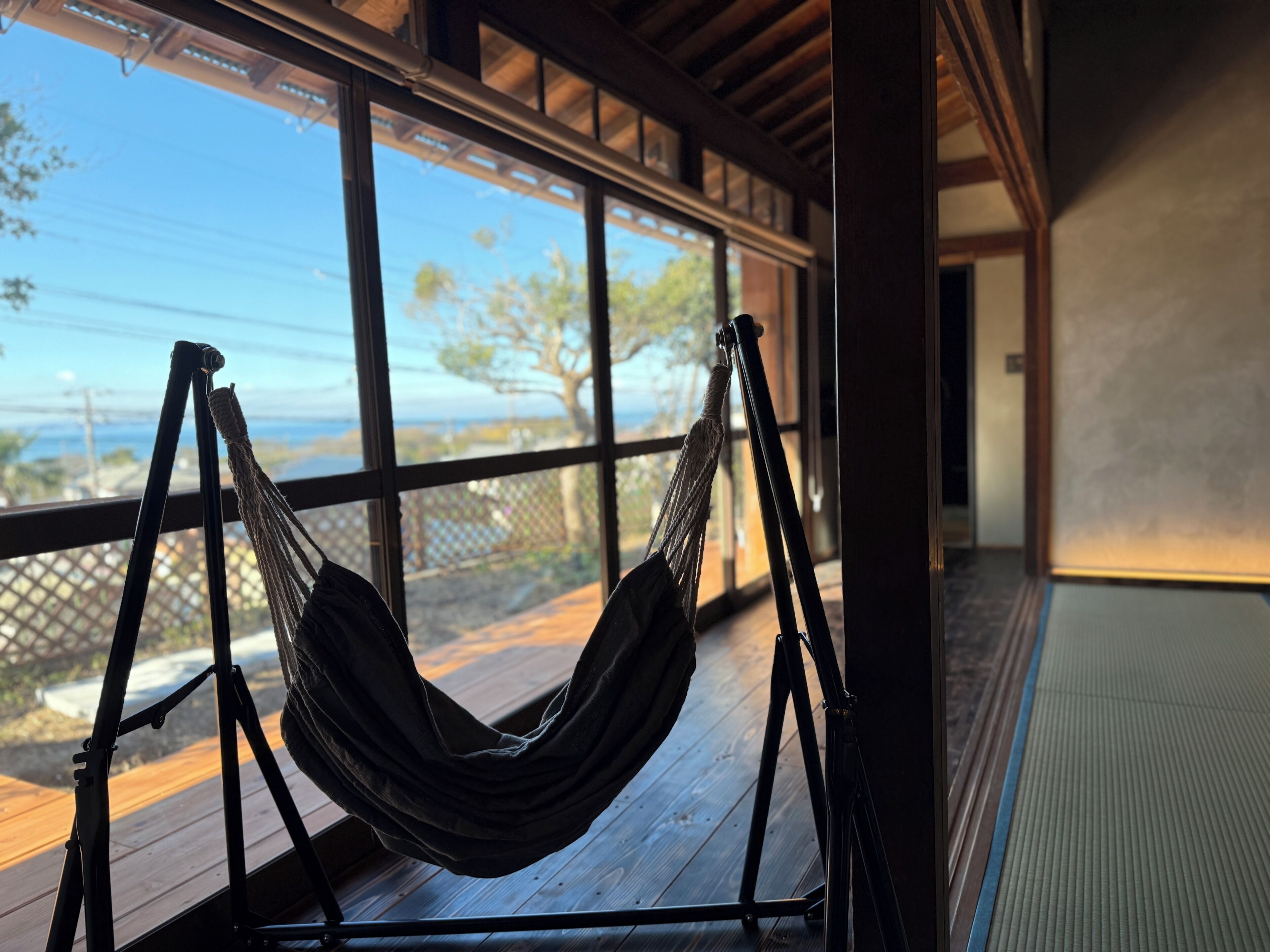 A hammock on a wooden deck with a view of the outdoors.