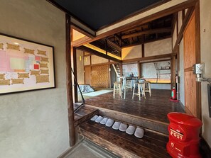 A room with a wooden floor, a table with stools, a fire extinguisher, and a framed map on the wall.
