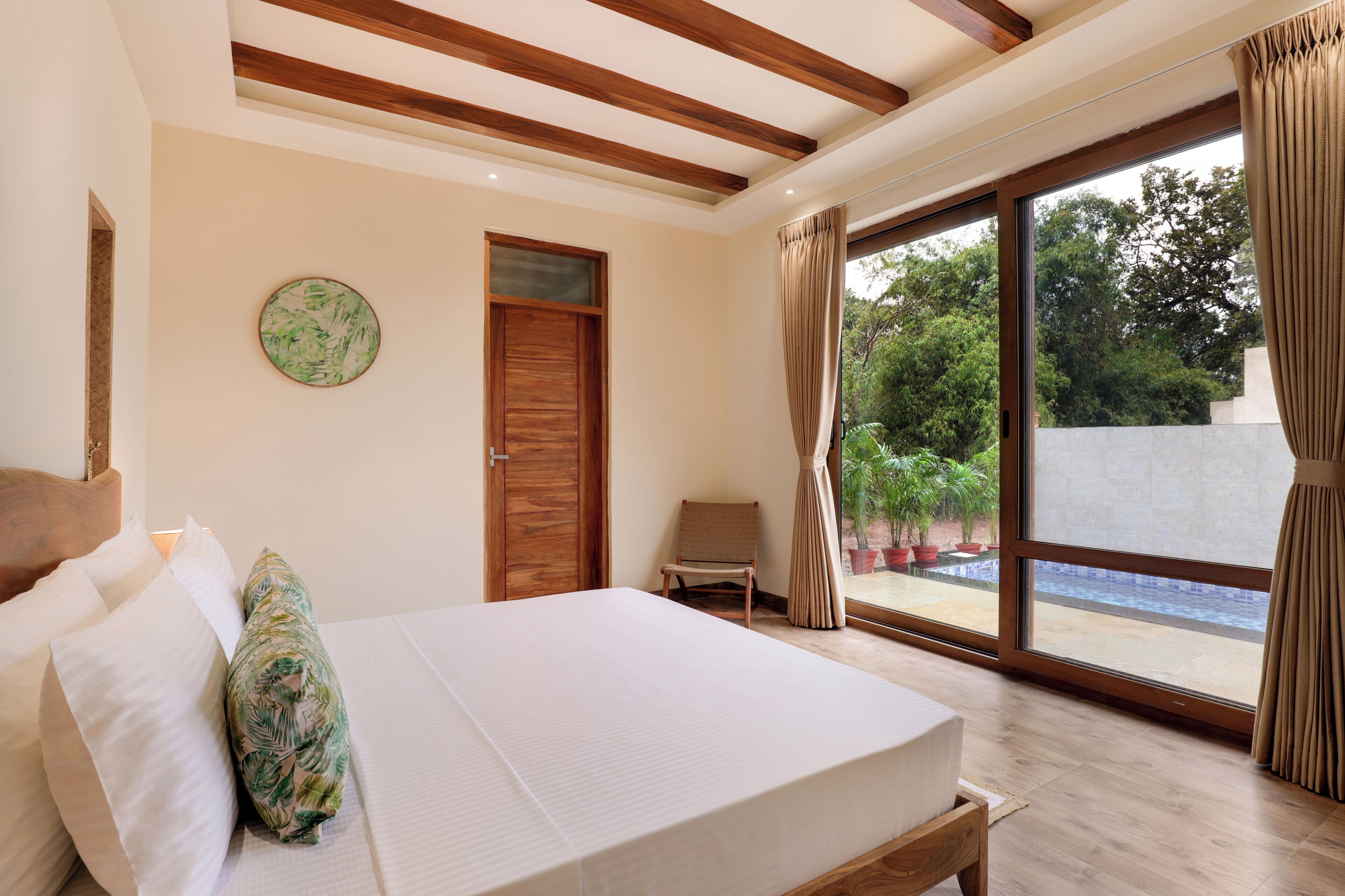Un dormitorio con cama, una silla, una puerta de madera y vistas a una piscina.