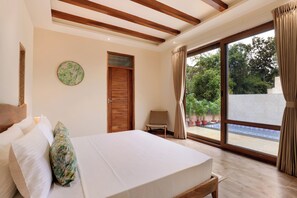 Un dormitorio con cama, una silla, una puerta de madera y vistas a una piscina.
