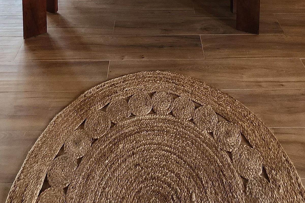 Una habitación con una cama grande, vigas de madera, un ventilador de techo y vistas al exterior.