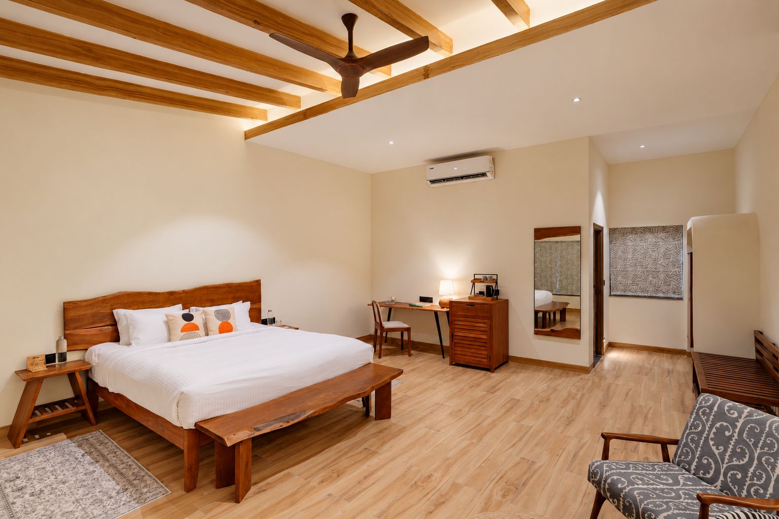 Un dormitorio con una cama de madera, un escritorio, una silla, un banco y un espejo.