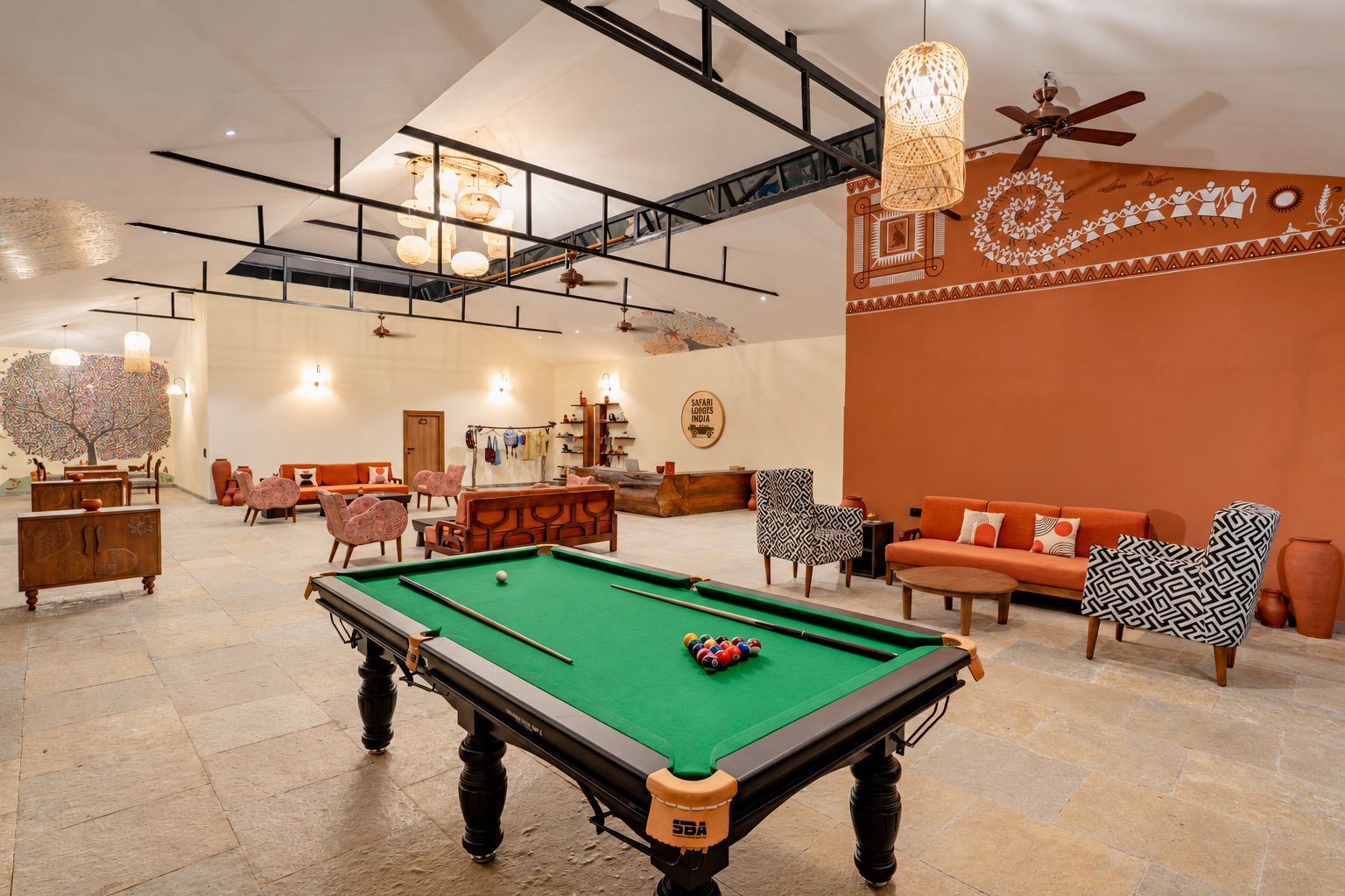 Un espacio interior amplio con mesa de billar, asientos y una pared decorativa.