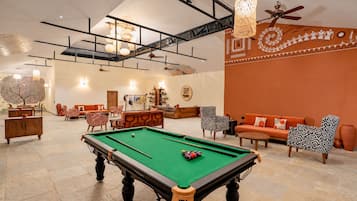 Un espacio interior amplio con mesa de billar, asientos y una pared decorativa.