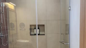 A shower area with a glass door, a toilet, and a sink.
