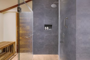 A modern shower with a glass door, a wooden bench, and a small shelf with decorative items.