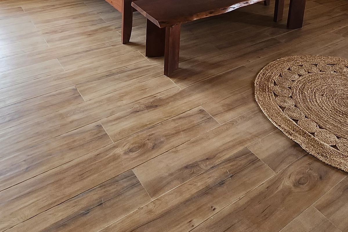 Un dormitorio con una cama de madera, una mesita de noche, un ventilador de techo y una alfombra tejida.