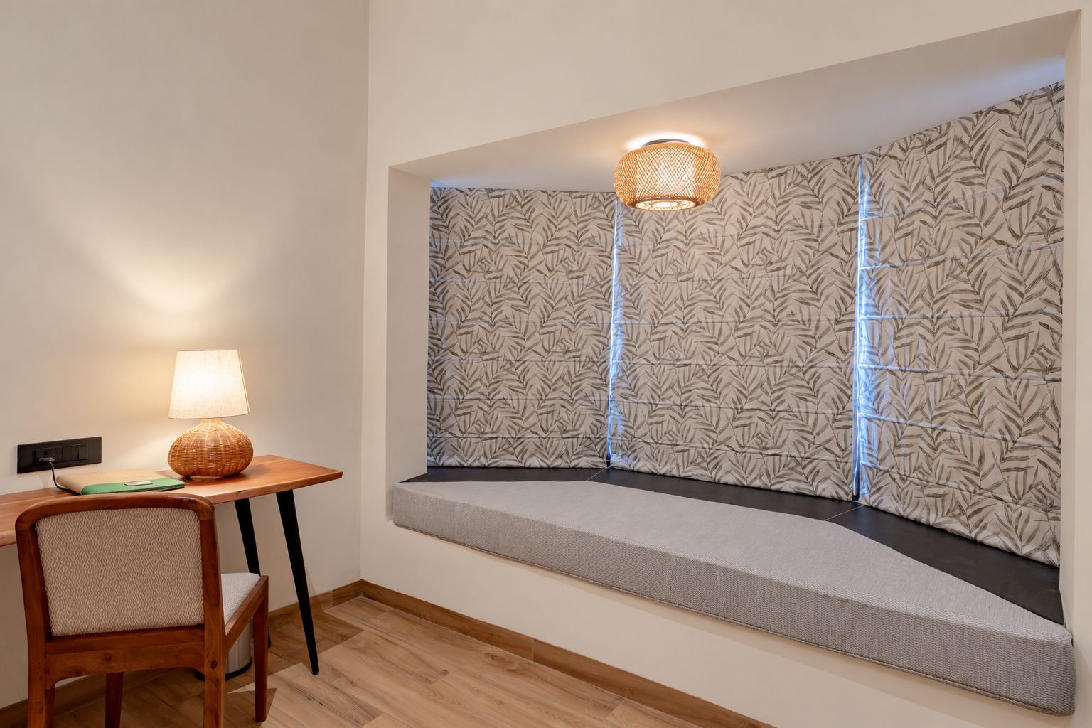Una habitación de esquina con un banco, una mesa con lámpara y una pared con diseño.