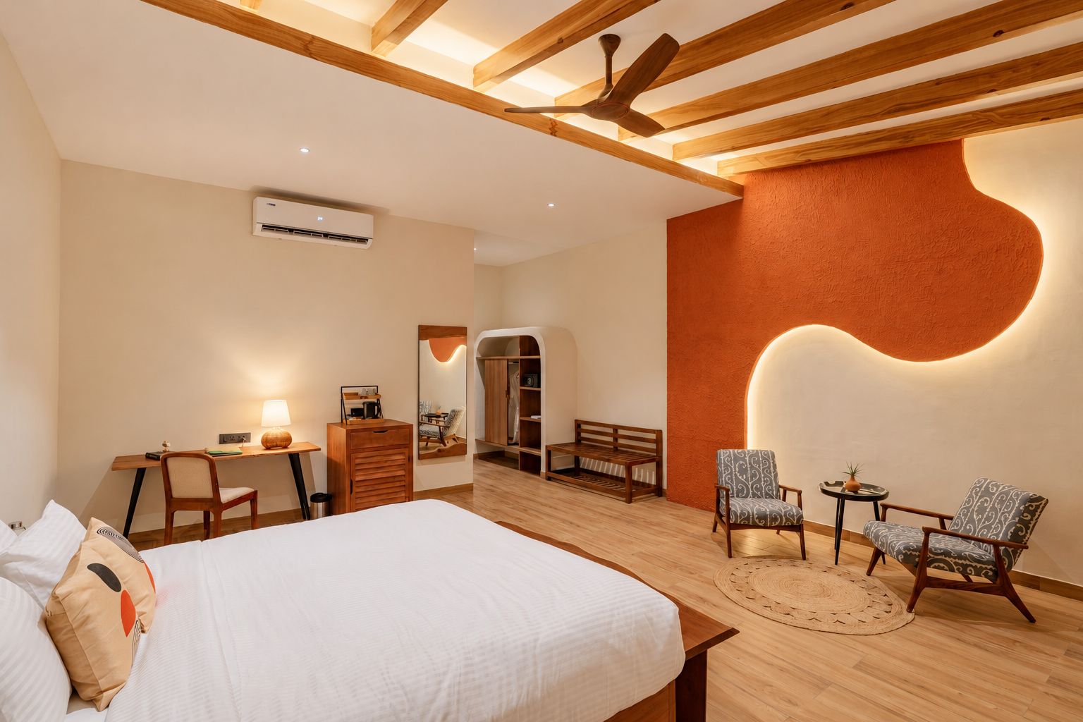 Habitación de hotel con cama, escritorio, armario y zona de estar.