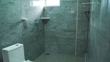 A bathroom with a toilet, a shower, and a window.