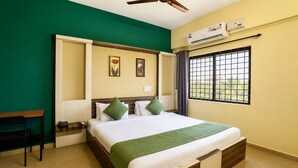 Habitación de hotel con cama, escritorio, silla, equipo de aire acondicionado y ventana con vistas.