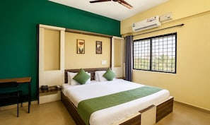 A hotel room with a bed, a desk, a chair, an air conditioning unit, and a window with a view.