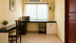 Una cocina compacta con microondas, lavamanos y ventana con cortinas.