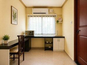 A compact kitchen with a microwave, sink, and a window with curtains.
