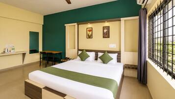 A hotel room with a bed, a desk, and a window with bars.