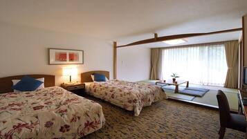 Habitación de hotel con dos camas, un escritorio, una silla, un televisor y una ventana con cortinas.