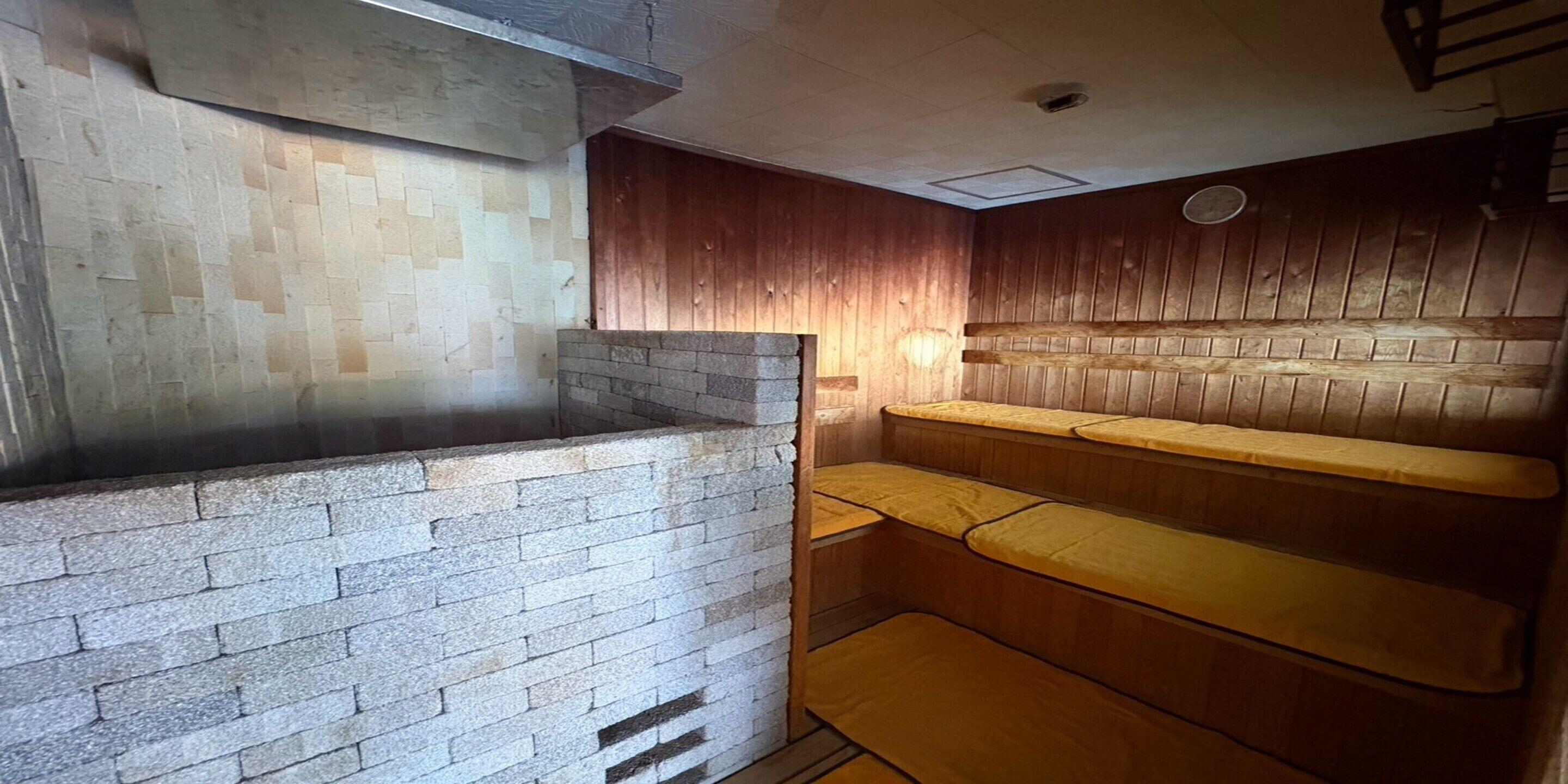 A sauna room with a stone bench and a wooden wall.