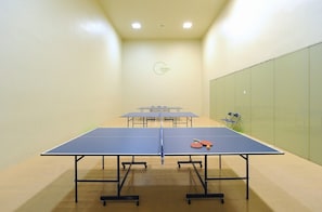 Una habitación con mesas de ping pong, sillas y un logotipo en la pared.