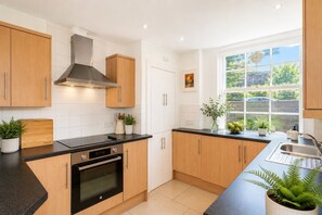 Eine moderne Küche mit Holzschränken, einer schwarzen Arbeitsplatte und einem Fenster mit Blick auf Grünfläche.