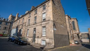 A historic stone building with multiple windows and a corner entrance. - 2 bedroom property in peaceful Edinburgh location (Edinburgh)