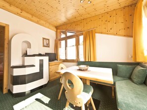 A cozy room with a wooden ceiling, a dining table with chairs, a sofa, and a window with curtains. - Appartements Lärchenhof, (Samnaun-Compatsch) by Interhome (Samnaun)