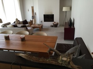 A modern living room with a wooden coffee table, a sofa, and a dining table.