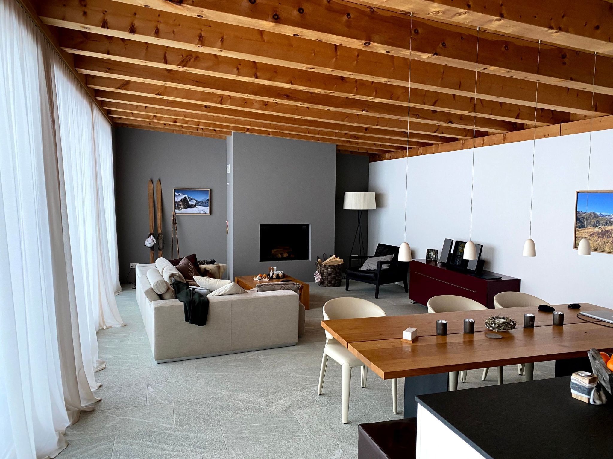 A modern living room with a fireplace, a dining area, and a sofa.