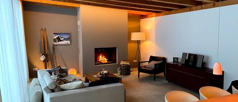 A cozy living room with a fireplace, a sofa, a dining table, and a lamp.