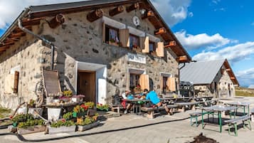 Ein Gebäude aus Stein mit Holzdach, Außenbestuhlung und einer Flagge auf dem Dach.