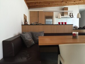 Een moderne keuken met houten kastjes, een eettafel en een bankje.