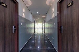 A corridor with doors marked 304 and 303, leading to a bright area with natural light.