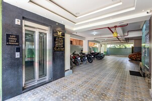 Vestíbulo de hotel con ascensor, alarma de emergencia y un cartel que indica las plantas.