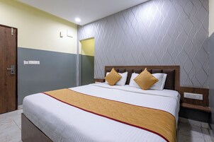 Una habitación de hotel con una cama, una puerta de madera, un interruptor de luz y una pared con un diseño geométrico.