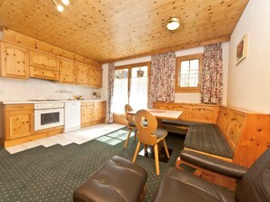 A cozy kitchen with wooden cabinets, a dining table, and a bench. - Appartements Lärchenhof, (Samnaun-Compatsch) by Interhome (Samnaun)