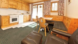 A cozy kitchen with wooden cabinets, a dining table, and a bench. - Appartements Lärchenhof, (Samnaun-Compatsch) by Interhome (Samnaun)