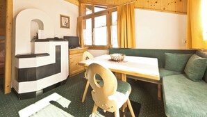 A compact room with a wooden ceiling, a dining table with chairs, a sofa, and a window with curtains. - Appartements Lärchenhof, (Samnaun-Compatsch) by Interhome (Samnaun)