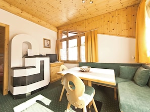 A compact room with a wooden ceiling, a dining table with chairs, a sofa, and a window with curtains. - Appartements Lärchenhof, (Samnaun-Compatsch) by Interhome (Samnaun)