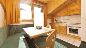 A cozy kitchen with wooden cabinets, a dining table, and a built-in oven. - Appartements Lärchenhof, (Samnaun-Compatsch) by Interhome (Samnaun)