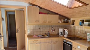 A compact kitchen with wooden cabinets, a built-in oven, and a skylight. - Rauher Kopf Vacation Rental, 50 m², 1–4 people, 2 bedrooms, 2 showers/toilets, kitchen (Bischofswiesen)